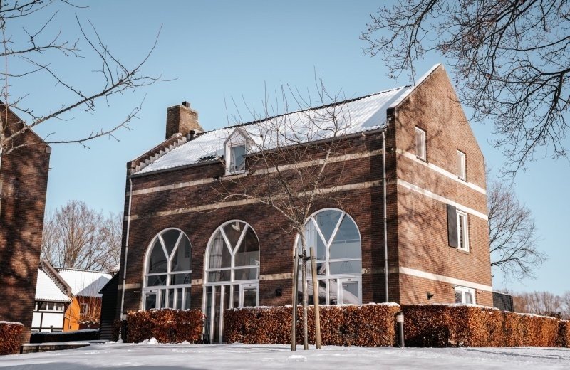 Uitzicht op vakantiepark De Mechelerhof in de winter met verse sneeuw rond de vakwerkappartementen in Mechelen, Zuid-Limburg